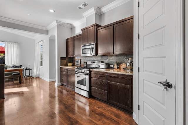 kitchen with dark brown cabinetry, stainless steel appliances, baseboards, decorative backsplash, and visible vents