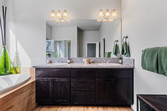 full bath with a sink, double vanity, a shower stall, and a bath