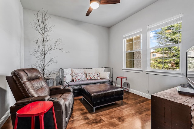 living area with dark wood-style flooring, a ceiling fan, and baseboards