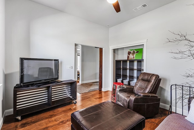 living area with visible vents, a ceiling fan, baseboards, and wood finished floors