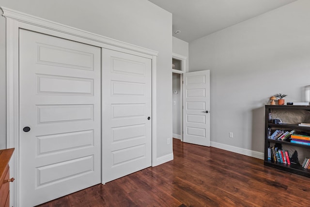 bedroom with a closet, baseboards, and dark wood-type flooring