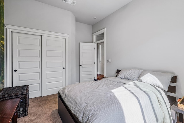 bedroom with dark colored carpet, visible vents, and a closet