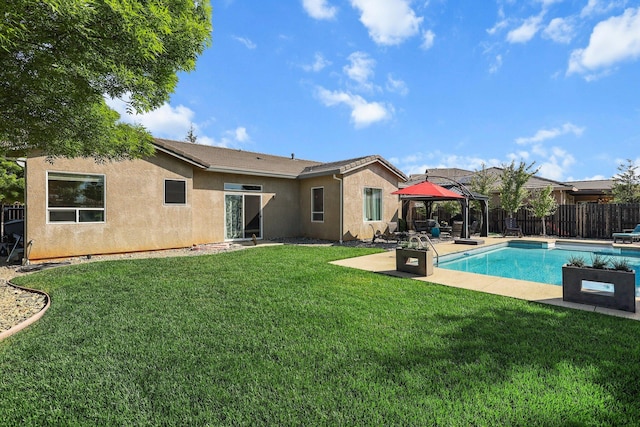 rear view of house featuring a patio, a fenced backyard, stucco siding, a gazebo, and a yard