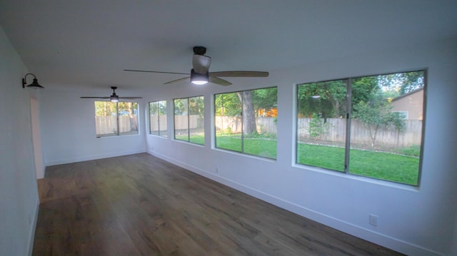 unfurnished sunroom featuring ceiling fan, baseboards, and wood finished floors