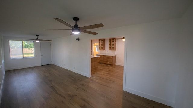 interior space featuring ceiling fan, baseboards, and wood finished floors