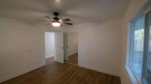 unfurnished bedroom featuring baseboards, wood finished floors, a closet, and ceiling fan