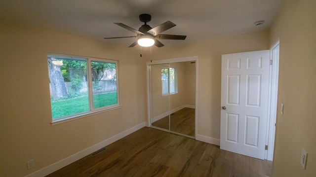 unfurnished bedroom with a ceiling fan, wood finished floors, a closet, baseboards, and visible vents