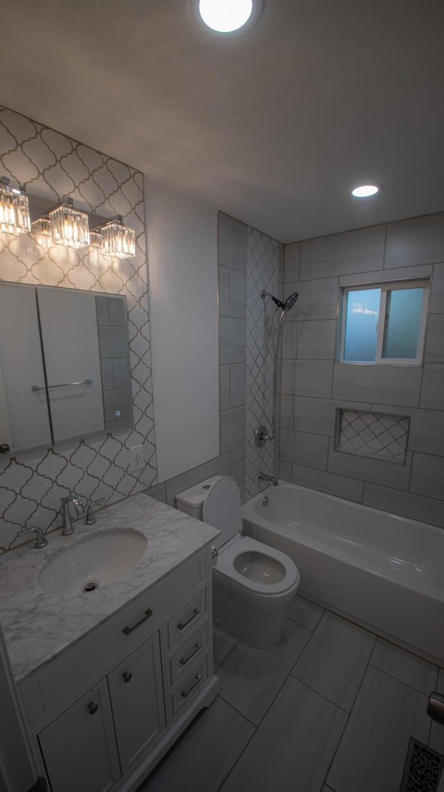 bathroom with toilet, tile walls, recessed lighting, shower / washtub combination, and vanity
