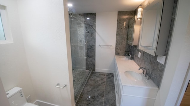 full bath with double vanity, toilet, tiled shower, and a sink