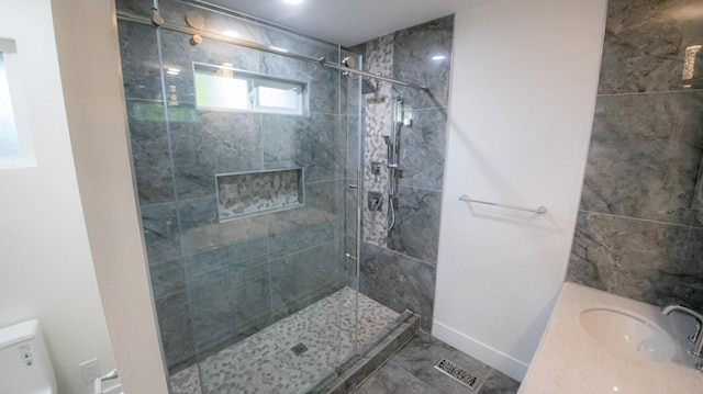 bathroom featuring a shower stall, toilet, baseboards, and a sink