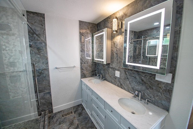 bathroom featuring a shower stall, baseboards, a sink, and double vanity