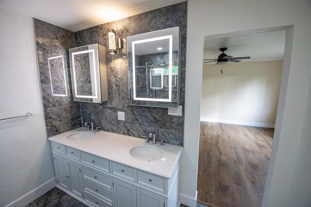 full bath featuring ceiling fan, baseboards, a sink, and double vanity