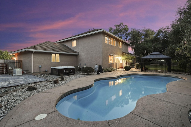 20340 Greenview Dr, Redding, CA 96002 - pool at dusk featuring a hot tub, a gazebo, a patio area, and a fenced backyard