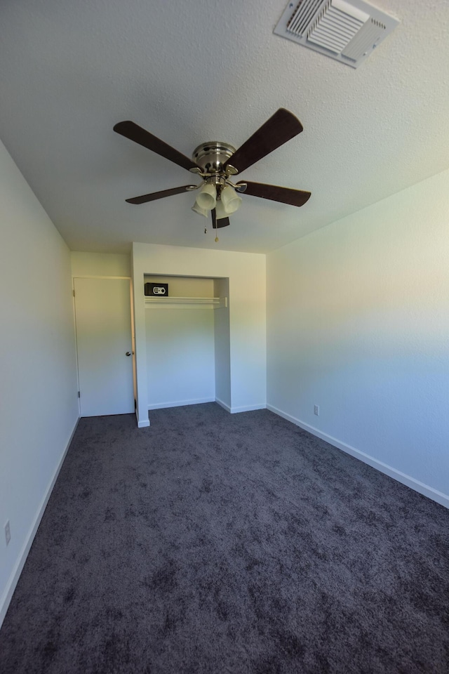 unfurnished bedroom with visible vents, baseboards, ceiling fan, and dark carpet