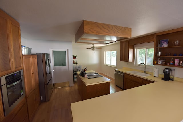 kitchen featuring a kitchen island, brown cabinets, a sink, light wood-style flooring, and stainless steel appliances