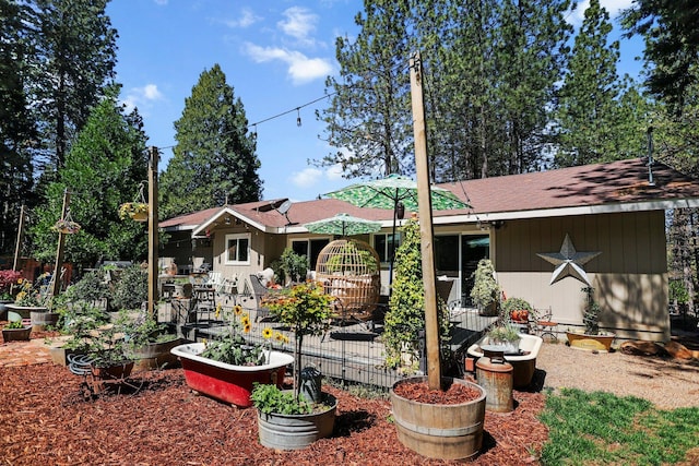 rear view of property featuring a patio and a vegetable garden