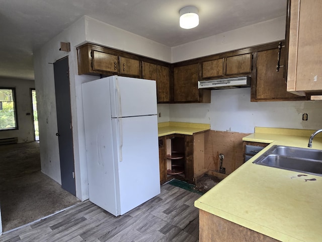 kitchen with freestanding refrigerator, under cabinet range hood, a sink, dark brown cabinetry, and light countertops