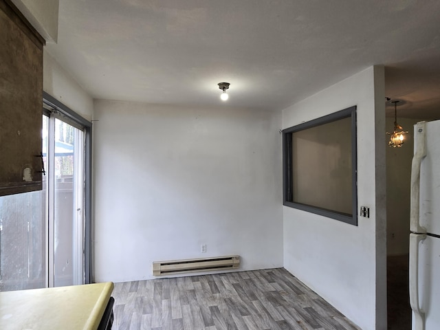 unfurnished room featuring a baseboard heating unit and wood finished floors