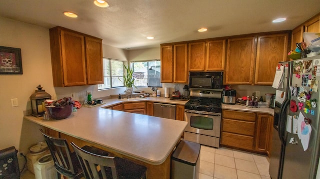 1695 Canter Ct, Redding, CA 96002 - kitchen with a sink, brown cabinetry, a peninsula, light countertops, and appliances with stainless steel finishes