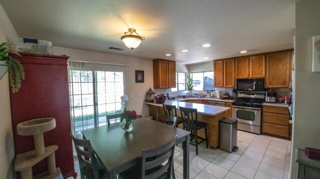 1695 Canter Ct, Redding, CA 96002 - kitchen featuring light tile patterned floors, brown cabinets, visible vents, stainless steel appliances, and a peninsula