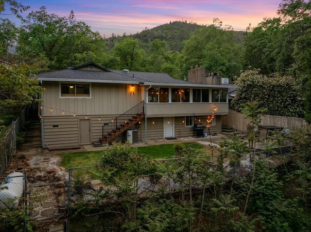 19817 Oak Knoll Dr, Lakehead, CA 96051 - rear view of house with a chimney, a shingled roof, a sunroom, stairway, and a fenced backyard