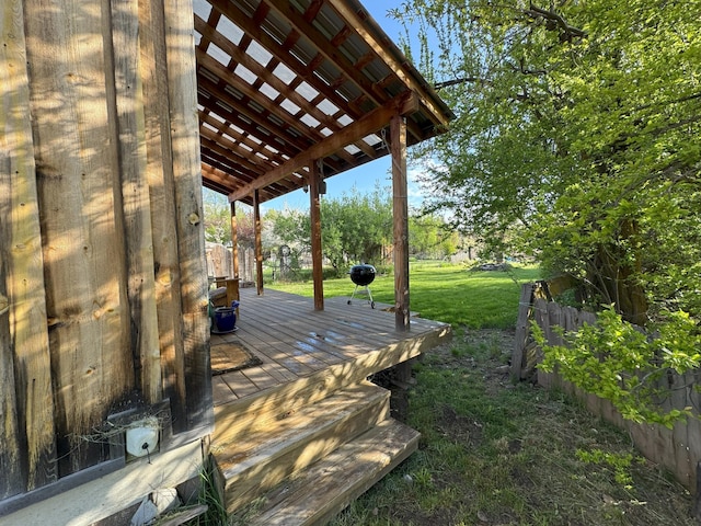 wooden terrace featuring a lawn and fence