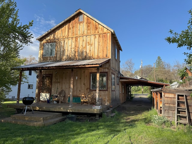 back of property with board and batten siding, a yard, a wooden deck, and metal roof