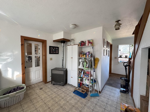 interior space with baseboards, a wood stove, light floors, and a textured ceiling