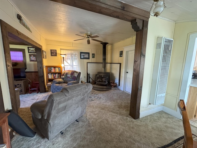 living area with a heating unit, carpet, ceiling fan, and a wood stove