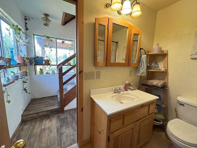 full bathroom with toilet, a textured wall, a chandelier, and wood finished floors