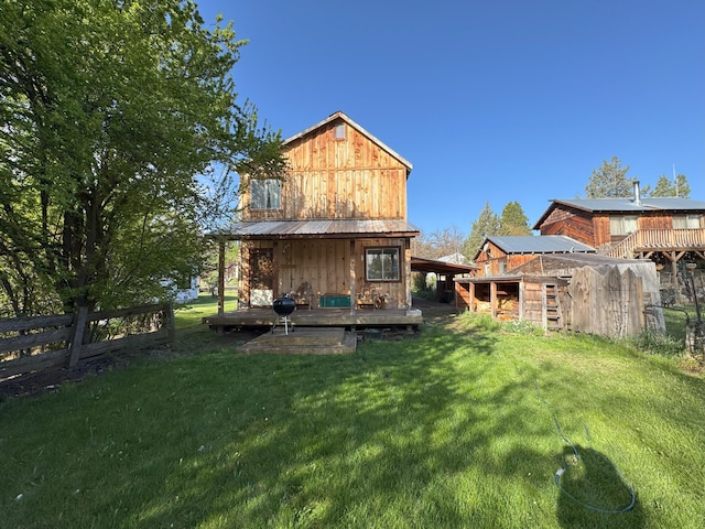 rear view of house featuring fence, metal roof, a yard, and an outbuilding