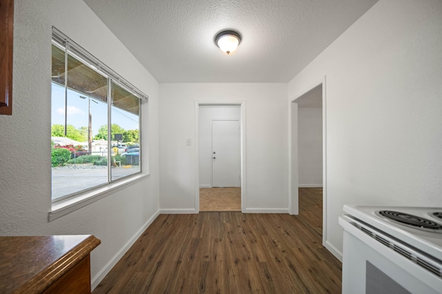 unfurnished dining area featuring a textured ceiling, dark wood-type flooring, and baseboards