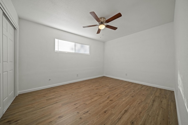 unfurnished bedroom featuring a closet, baseboards, a ceiling fan, and wood finished floors