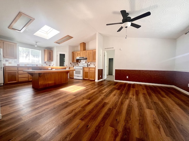 kitchen with white appliances, under cabinet range hood, a center island, open floor plan, and dark wood-type flooring