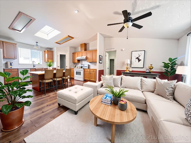 living area with ceiling fan, vaulted ceiling, and wood finished floors