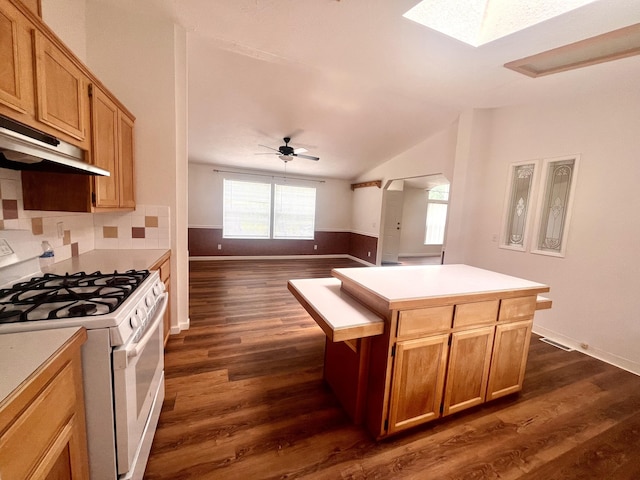 kitchen featuring white range with gas stovetop, lofted ceiling with skylight, dark wood-style flooring, and light countertops