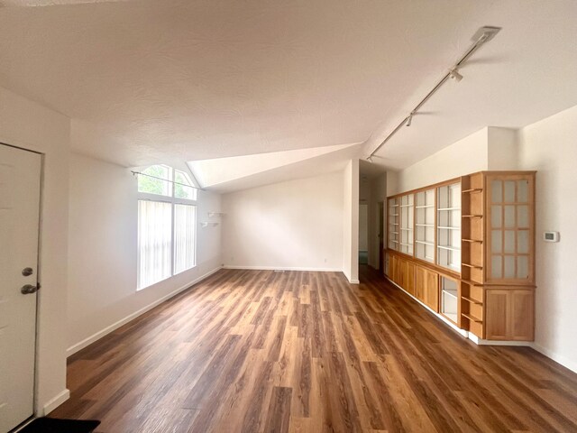 additional living space with baseboards, wood finished floors, and vaulted ceiling