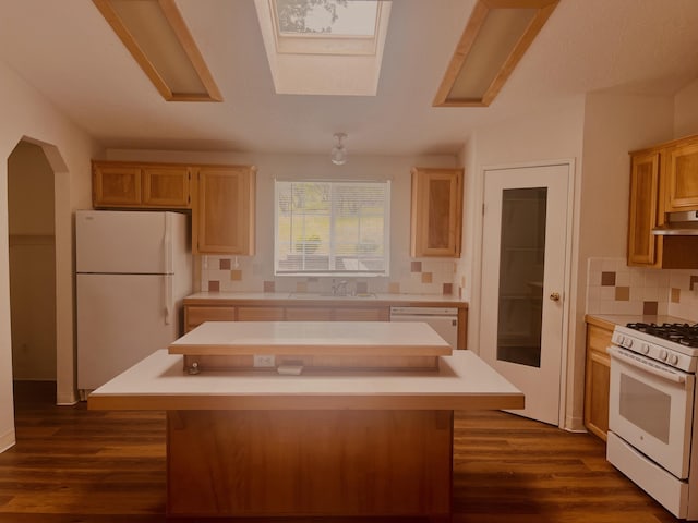 kitchen featuring white appliances, decorative backsplash, light countertops, a center island, and dark wood-type flooring