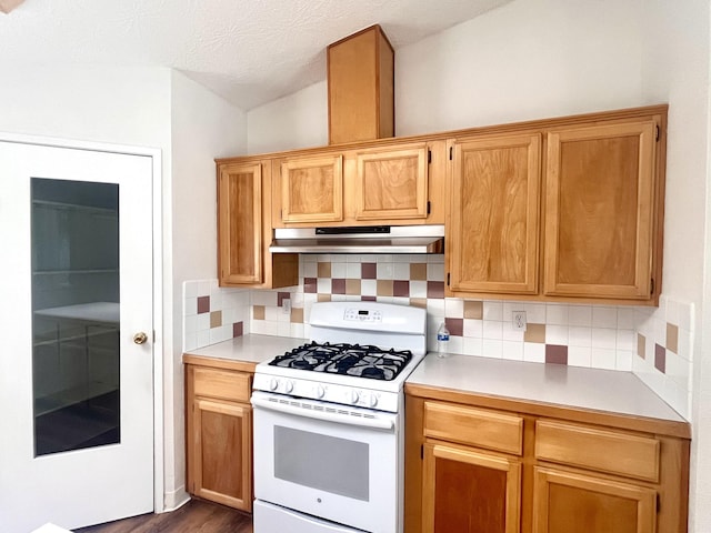 kitchen with white gas range oven, light countertops, decorative backsplash, and under cabinet range hood