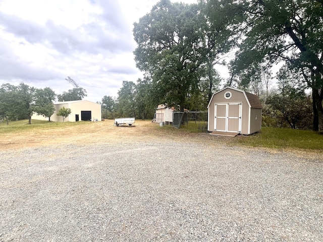 view of yard featuring an outbuilding, a storage shed, driveway, and a garage