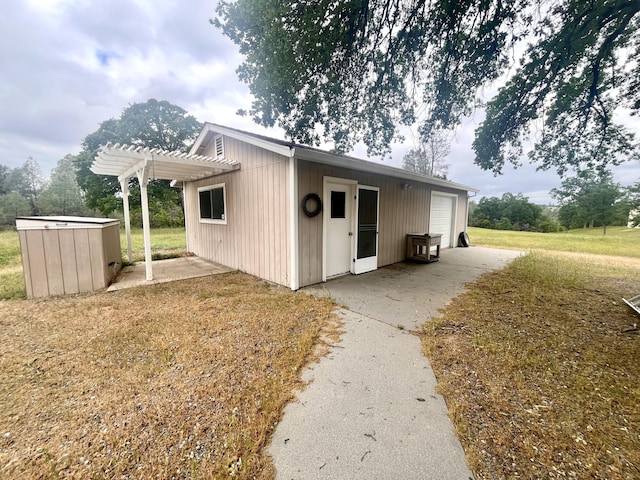 exterior space with an outbuilding, a pergola, a garage, and a patio area