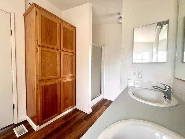 bathroom with wood finished floors, visible vents, a stall shower, and a sink