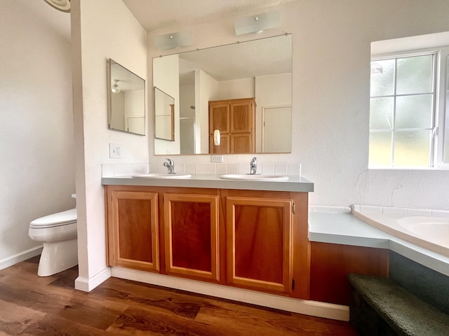 full bath with wood finished floors, toilet, double vanity, and a sink