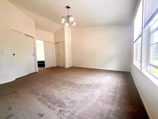 unfurnished bedroom with two closets, a chandelier, vaulted ceiling, carpet flooring, and baseboards