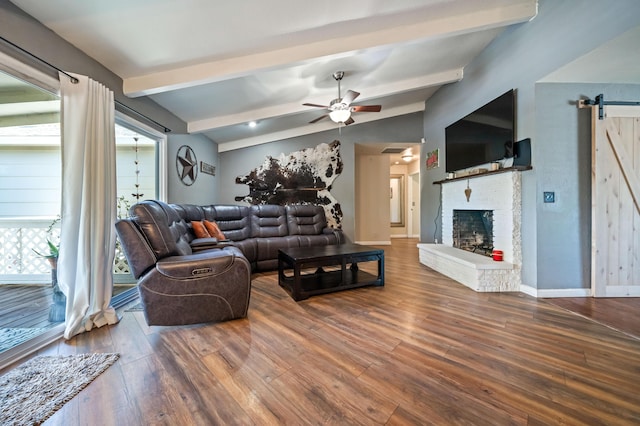 living area featuring plenty of natural light, a barn door, ceiling fan, and wood finished floors
