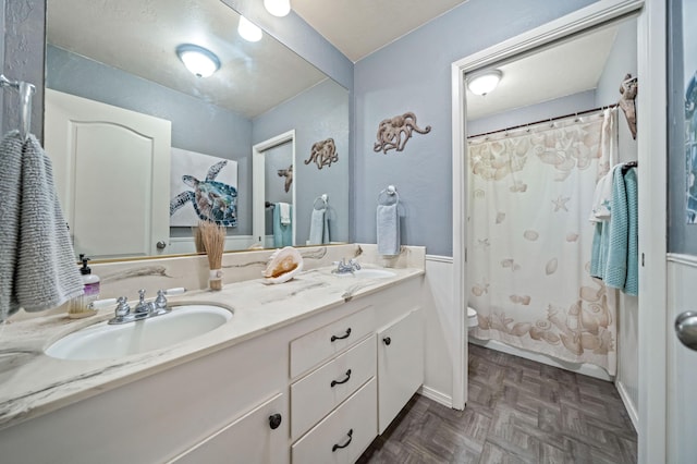 full bathroom featuring double vanity, toilet, a shower with curtain, and a sink
