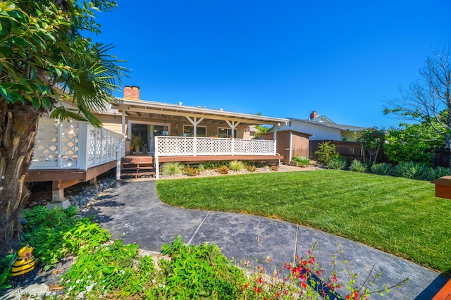 view of front facade with a chimney, a front yard, a storage shed, a wooden deck, and fence