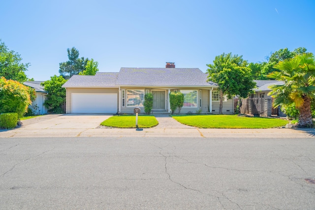 ranch-style house featuring concrete driveway, a chimney, a front yard, and a garage