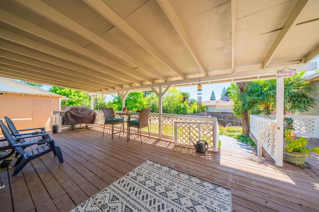 wooden terrace featuring fence and a grill
