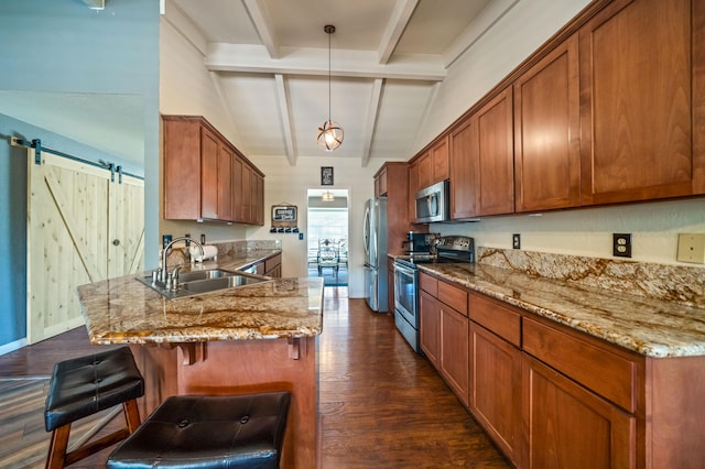 kitchen with brown cabinetry, appliances with stainless steel finishes, a sink, lofted ceiling with beams, and a peninsula